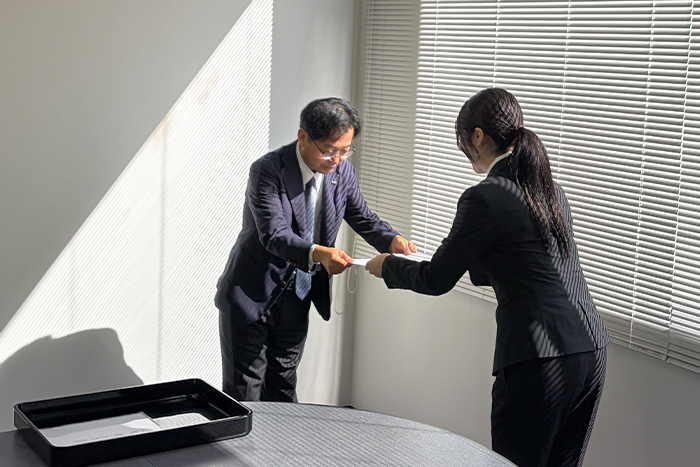 エル・ローズ管理部長から内定者へ内定書を手渡す様子